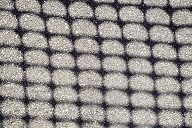 Pattern made with shadow of fence on asphalt