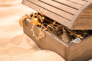 Open wooden treasure chest on sand, closeup