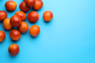 Many ripe sicilian oranges on light blue background, flat lay. Space for text