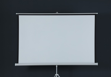 Blank projection screen near black wall indoors. Space for design