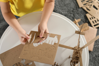 Photo of Little boy making carton toys at table indoors, top view. Creative hobby
