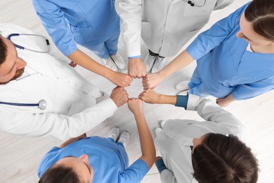 Team of medical doctors putting hands together indoors, above view