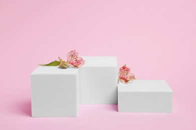 Scene for product presentation. Podiums of different geometric shapes and flowers on pink background