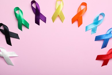 Colorful ribbons on pink background, flat lay with space for text. World Cancer Day