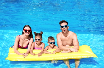 Happy family with inflatable mattress in swimming pool