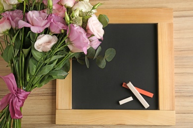 Flat lay composition with flowers and small blackboard for Teacher's day on wooden background