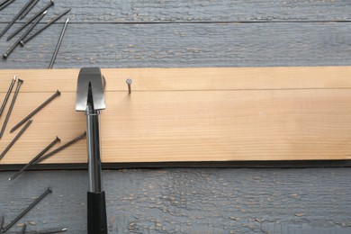 Photo of Hammering nails into plank on grey wooden table, flat lay. Space for text