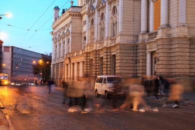 Photo of People crossing city street at evening, long exposure effect