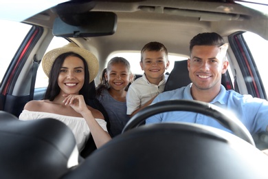 Happy family in car on road trip, view from outside