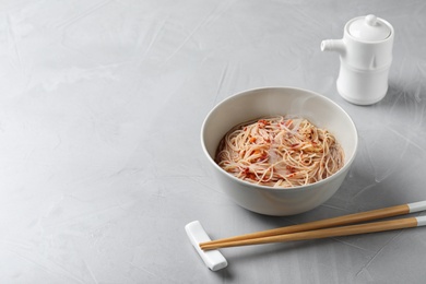 Photo of Bowl of hot noodles with broth on table. Space for text