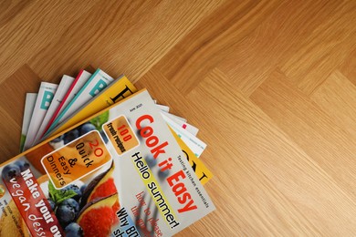 Photo of Many magazines on wooden background, top view. Space for text