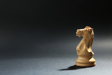 White wooden chess knight on dark background. Space for text