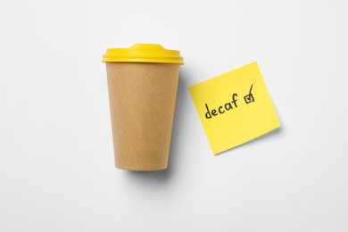 Photo of Takeaway coffe cup, note with word Decaf and checkbox on white background, flat lay