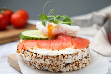 Crunchy buckwheat cakes with salmon, poached egg and cucumber slices served on board, closeup