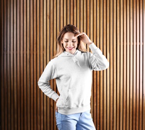 Photo of Portrait of woman in hoodie sweater on wooden background. Space for design