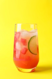 Photo of Tasty summer watermelon drink with lime in glass on yellow background