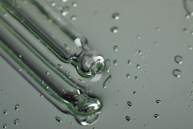 Photo of Pipette near serum drops on beautiful mirror, closeup with space for text. Toned in grey