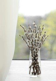 Beautiful pussy willow branches in glass vase on window sill indoors