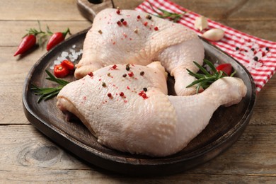 Raw chicken leg quarters and ingredients on wooden table