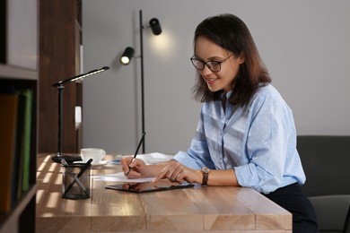 Woman with modern tablet learning at table indoors