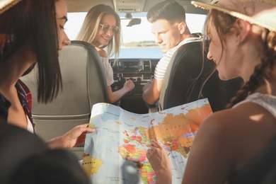 Happy friends with map in car on road trip