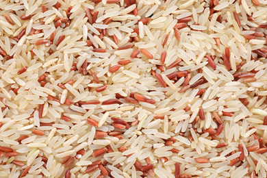 Mix of brown and polished rice as background, top view