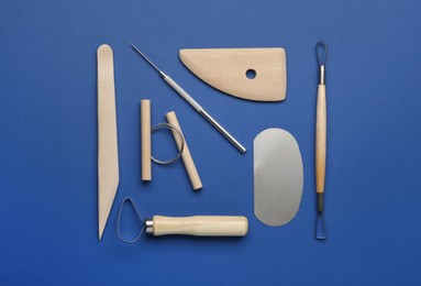 Photo of Set of clay modeling tools on blue background, flat lay