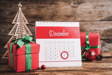 Calendar with marked Boxing Day date near gifts and decorative Christmas tree on wooden table
