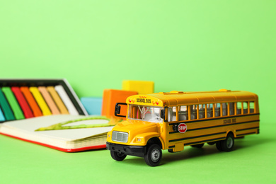 School bus model and stationery on green background. Transport for students