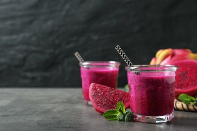 Delicious pitahaya smoothie, fruits and fresh mint on grey table, space for text