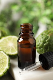 Glass bottle of bergamot essential oil and dropper on table