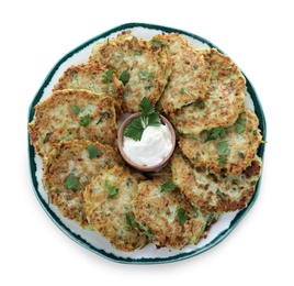 Delicious zucchini fritters with sour cream on white background, top view