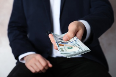 Closeup view of man in suit offering money indoors