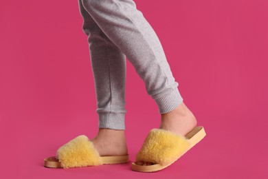 Photo of Woman in fluffy slippers on pink background, closeup