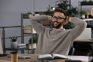 Happy man relaxing at workplace in office