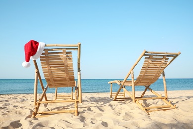Photo of Sun loungers and Santa's hat on beach. Christmas vacation
