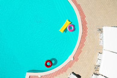 Image of Inflatable rings and mattress floating in swimming pool, top view. Summer vacation