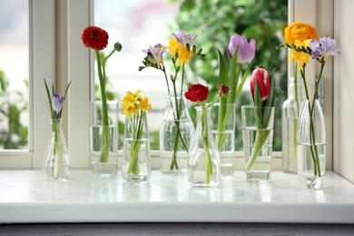 Photo of Beautiful spring flowers in glassware on window sill