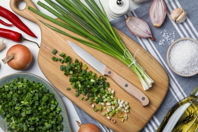 Chopped green spring onion, stems and other ingredients on white table, flat lay
