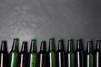 Photo of Tasty beer in bottles on black background, flat lay. Space for text