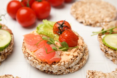 Crunchy buckwheat cakes with salmon, tomatoes and greens on white table, closeup