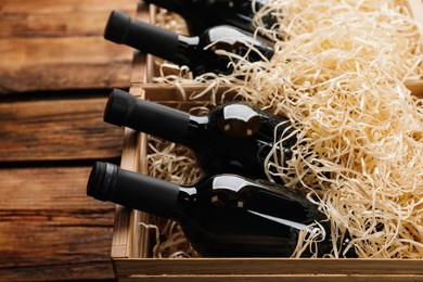 Crates with bottles of wine on wooden background, closeup
