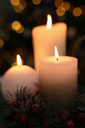 Beautiful burning candles against Christmas lights, closeup