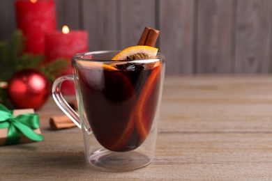 Glass cup of aromatic mulled wine on wooden table