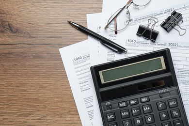 Calculator, documents, glasses and stationery on wooden table, flat lay with space for text. Tax accounting