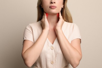 Image of Young woman doing thyroid self examination on beige background, closeup