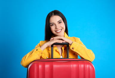 Beautiful woman with suitcase for summer trip on blue background. Vacation travel