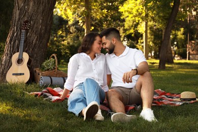 Lovely couple spending time together on picnic plaid in park