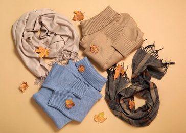 Flat lay composition with sweater and dry leaves on beige background. Autumn season