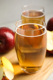Delicious cider and ripe red apples on wooden board, closeup